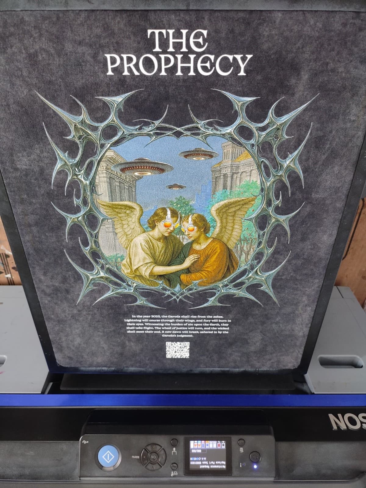 Manual screen printing press applying white ink on black cotton T-shirt